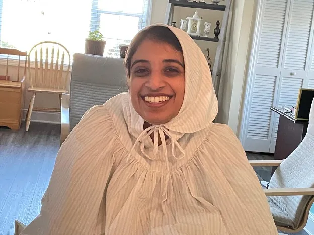 Sana, smiling, in a pale striped headscarf — the photo from her biodata