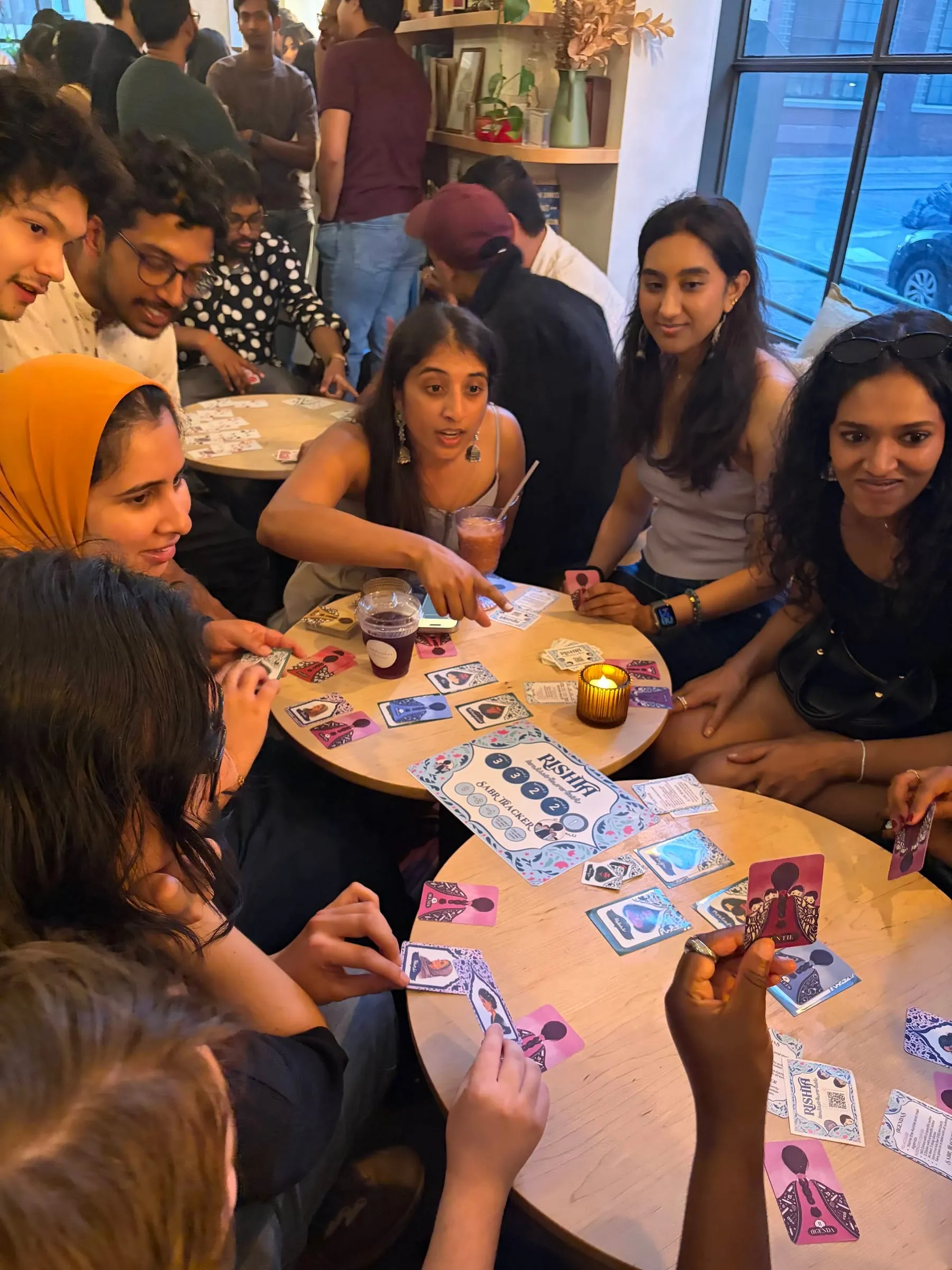 Players round a wooden cafe table at Fontainhaus, cards and a lit candle between them