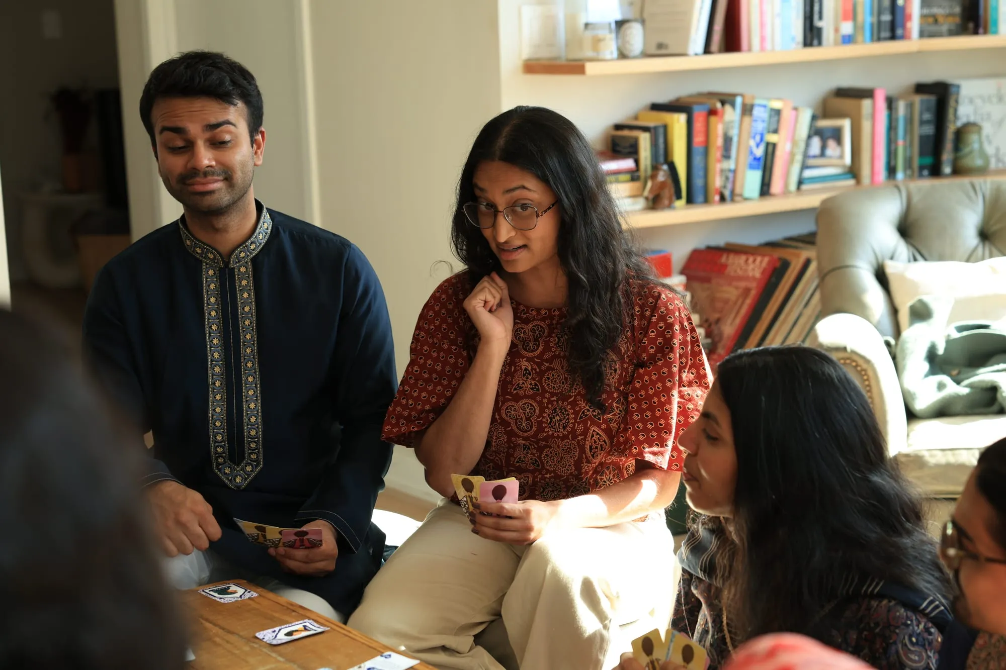 Two players in front of a bookshelf, one holding an agenda card close