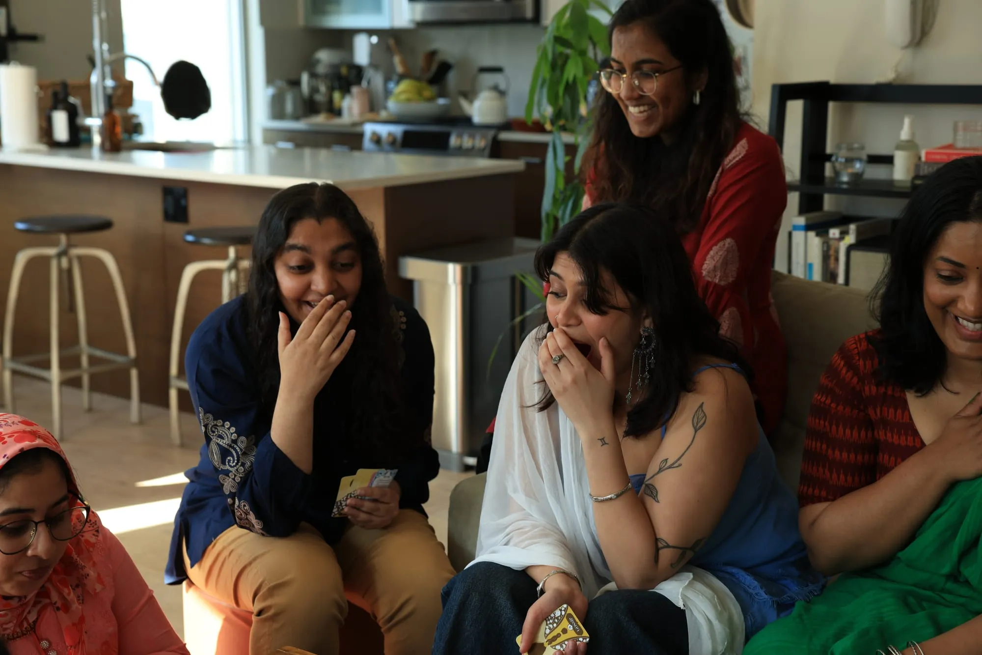 Two players in a kitchen covering their mouths, gasping at a card